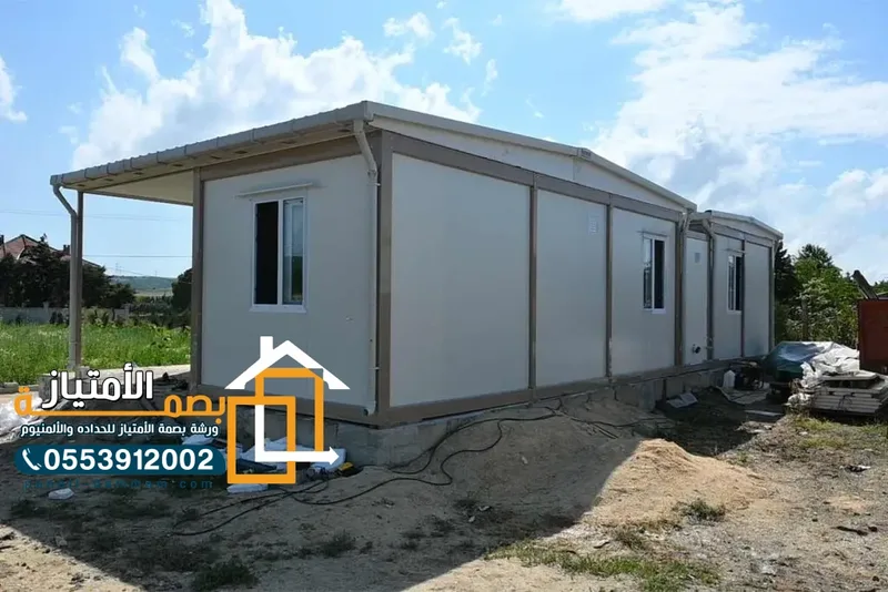 ملحق ساندوتش بانل بجدران رمادية ونوافذ ألمنيوم في موقع مفتوح