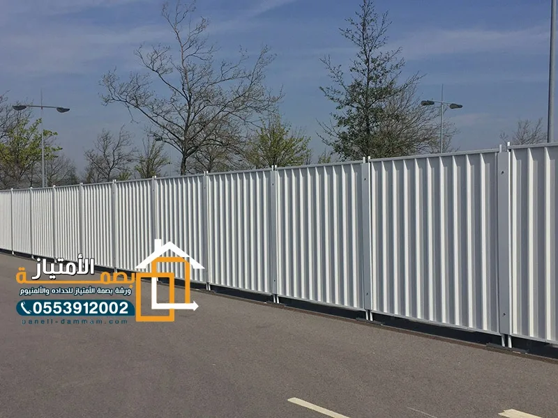 سور تحويش معدني أبيض حول موقع بجانب طريق