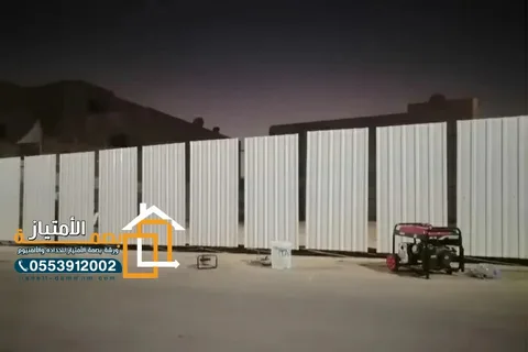 سور تحويش معدني أبيض حول موقع عمل ليلاً